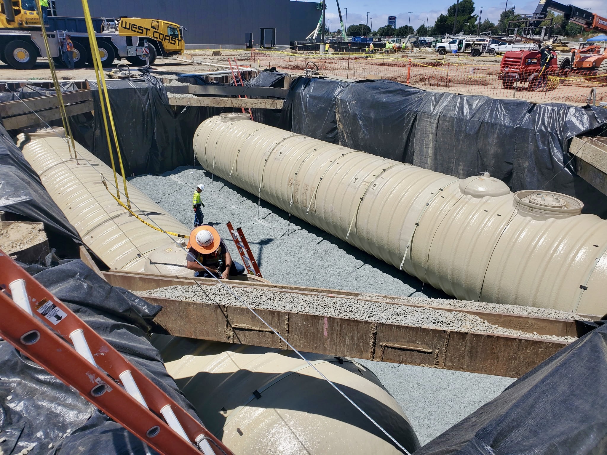 Vasquez crew guiding a tank into an excavated trench on a jobsite
