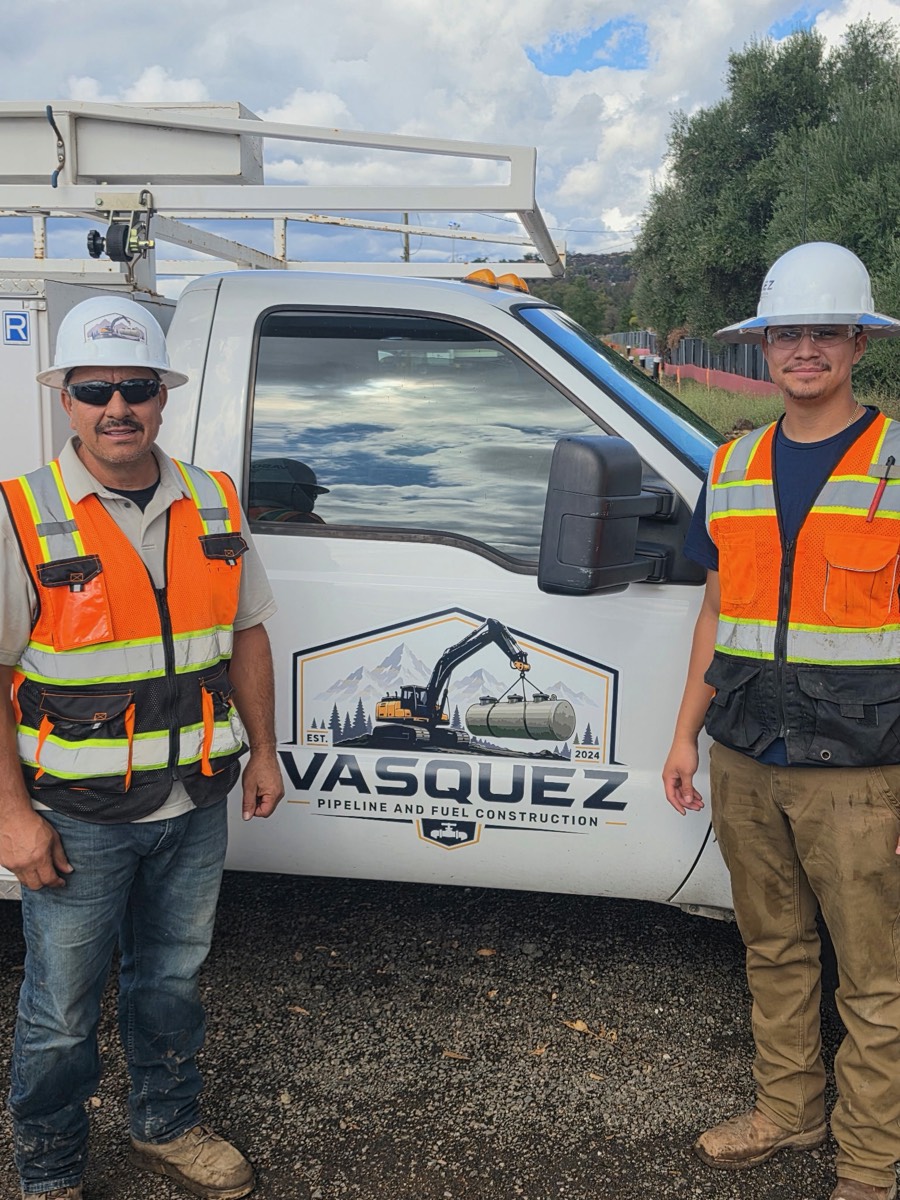 Frank Vasquez and a crew member at the door of a Vasquez service truck with the company logo