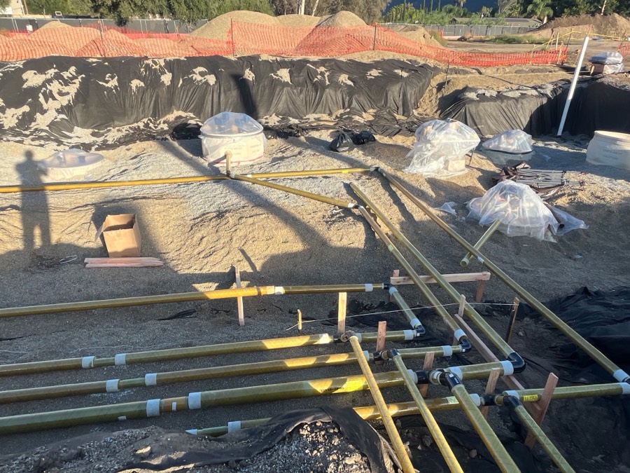Wrapped sumps and product piping laid out across a gravel-bedded tank pit