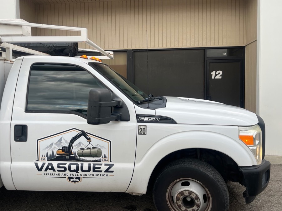 A white Vasquez service truck with the company logo on the door