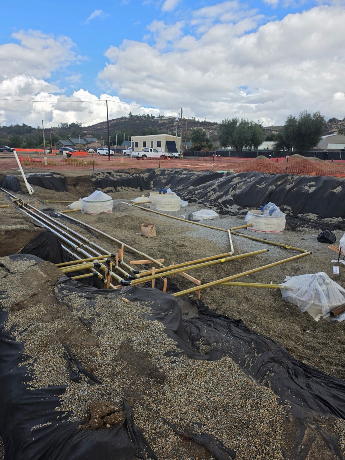 Fiberglass product piping run through a gravel-bedded trench to the sumps at a fueling station build